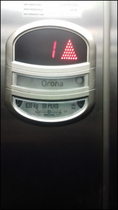 Na wyświetlaczu w windzie jest nr 1 oraz symbol jazdy w górę.